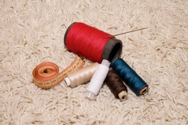 İplik, iğne, metre farklı renkte makaralar beyaz arkaplanda yatar