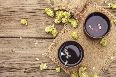 Taze yabani zıpzıp ile bir fincan sakinleştirici bitki çayı. Eski tahta arka planda çuval içinde kozalaklar