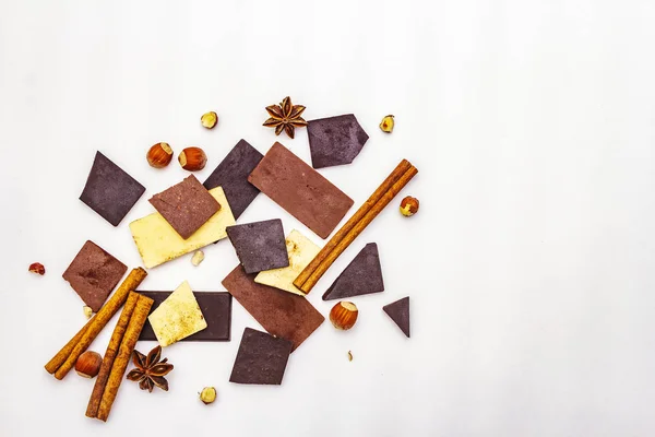 Surtido de diferentes tipos de chocolate, especias y avellanas sobre blanco — Foto de Stock