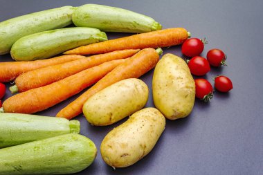 Taze sebzeler siyah taş arka plan pişiriyor.