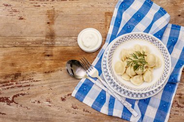 Taze ekşi kremalı sıcak etli börek. Geleneksel Rus pelmeni, ravioli, yeşillik. Eski tahta tablolar, kopyalama alanı, üst görünüm