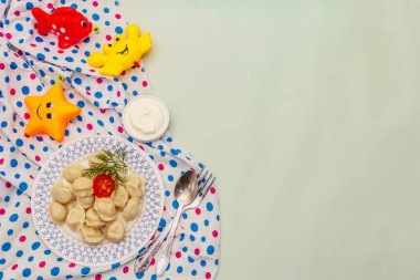 Taze ekşi kremalı sıcak etli börek. Ev yapımı sağlıklı çocuk mamaları, komik oyuncaklar. Açık yeşil arkaplan, üst görünüm