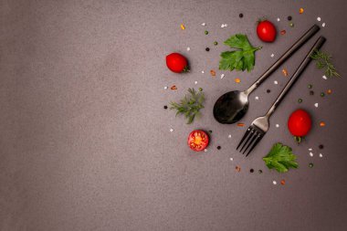 Mutfak geçmişi. Yemek pişirme konsepti. Çatal bıçak takımı, taze sebzeler, baharatlar, otlar. Moda siyah taş zemin, kopyalama alanı, üst görünüm