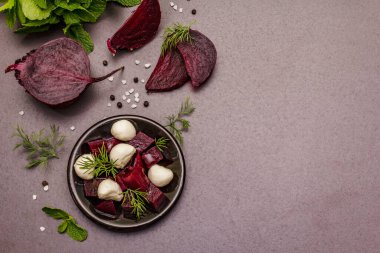 Mutfak geçmişi. Yemek pişirme konsepti. Fırında pancar salatası, bebek mozzarella, taze yeşillikler. Moda siyah taş zemin, üst manzara.