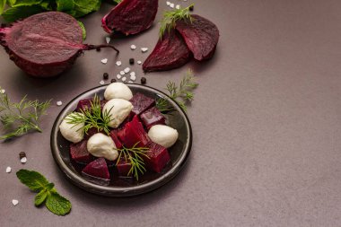 Mutfak geçmişi. Yemek pişirme konsepti. Fırında pancar salatası, bebek mozzarella, taze yeşillikler. Moda siyah taş zemin, kopyalama alanı