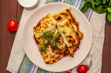 Sıcak aperatif, peynirli ve otlu pita ekmeği. Vejetaryen sağlıklı yiyecekler. Ahşap masa arkaplanı, üst görünüm