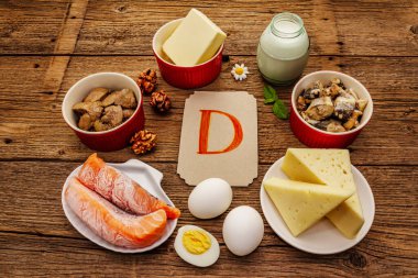 D vitamini, peynir, yumurta, tereyağı, fındık, süt, sardalya, somon, ciğer içeren yiyecekler. Eski tahta arka plan