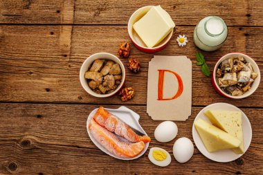 D vitamini, peynir, yumurta, tereyağı, fındık, süt, sardalya, somon, ciğer içeren yiyecekler. Eski tahta arka plan
