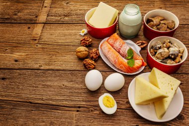 D vitamini, peynir, yumurta, tereyağı, fındık, süt, sardalya, somon, ciğer içeren yiyecekler. Eski tahta arka plan, metin için yer