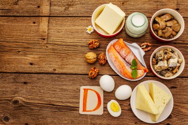 D vitamini, peynir, yumurta, tereyağı, fındık, süt, sardalya, somon, ciğer içeren yiyecekler. Eski tahta arka plan