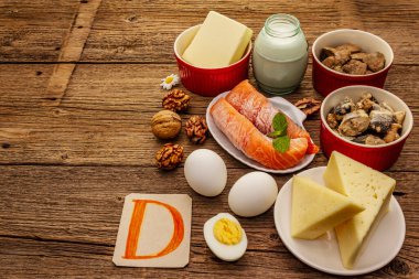 D vitamini, peynir, yumurta, tereyağı, fındık, süt, sardalya, somon, ciğer içeren yiyecekler. Eski tahta arka plan
