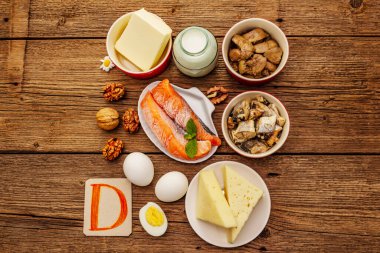 D vitamini, peynir, yumurta, tereyağı, fındık, süt, sardalya, somon, ciğer içeren yiyecekler. Eski tahta arka plan