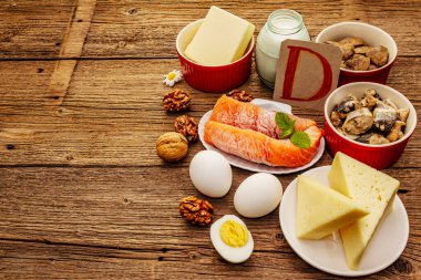 D vitamini, peynir, yumurta, tereyağı, fındık, süt, sardalya, somon, ciğer içeren yiyecekler. Eski tahta arka plan