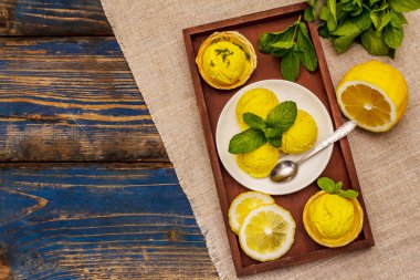 Naneli limonlu dondurma. Ferahlatıcı yaz tatlıları, olgun meyveler, mis kokulu yapraklar. Tahta kaplama arka plan, üst görünüm