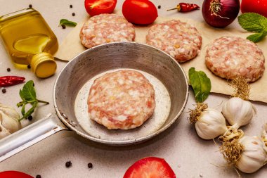 Çiğ pirzola, taze sebze, baharat, zeytinyağı. Klasik tava, piknik ya da barbekü pişirme konsepti. Taş beton arka plan, kapat