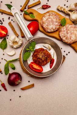 Çiğ ve kızarmış pirzola, taze sebze, baharat, zeytinyağı. Klasik tava, piknik ya da barbekü pişirme konsepti. Taş beton zemin, üst görünüm