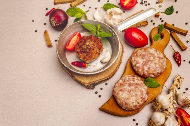 Çiğ ve kızarmış pirzola, taze sebze, baharat, zeytinyağı. Klasik tava, piknik ya da barbekü pişirme konsepti. Taş beton arkaplan, kopyalama alanı