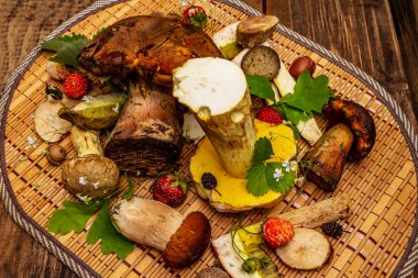 Taze orman mantarları. Türlü gurme porcini ve boletus, meşe yaprağı, çilek. Eski tahta arka plan, kapat