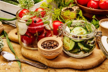 Sebze turşusu. Yemek pişirme süreci, baharatlar, taze kokulu bitkiler. Olgun domatesler, salatalıklar, eski ahşap masa