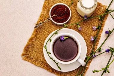 Faydalı hindiba içeceği ve çiçekler. Sağlıklı bitkisel içecek, kahve yerine. Diyet kahvaltı, taş beton arka plan, üst manzara.