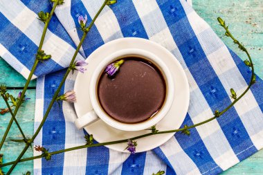 Faydalı hindiba içeceği ve çiçekler. Sağlıklı bitkisel içecek, kahve yerine. Diyet kahvaltı, modaya uygun turkuaz ahşap arka plan, üst manzara.