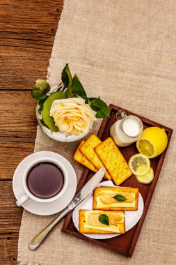 Sağlıklı kahvaltı. Bir fincan kahve (siyah çay), süt, tereyağlı kraker ve somon. Günaydın iyi ruh hali, eski ahşap arka plan, üst manzara