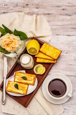 Sağlıklı kahvaltı. Bir fincan kahve (siyah çay), süt, tereyağlı kraker ve somon. Günaydın iyi ruh hali, eski ahşap arka plan, üst manzara