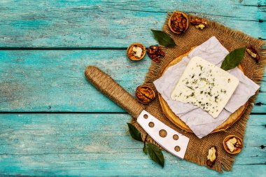 Küflü peynir. Peynir tabağı için. Fındık, kokulu defne yaprakları, bıçak. Moda turkuaz tahta tahta arka plan, üst görünüm