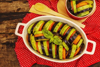 Pişirmek için taze sebzeler. Zeytinyağı, patlıcan, kabak, havuç, baharat ve fesleğen. Eski ahşap zemin, üst manzara