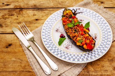 Karniyarik geleneksel Türk yemekleri. Kıyma, domates, yeşillik ve susamlı patlıcan dolması. Tabak eski ahşap bir masada servis edildi, kopyalama alanı.