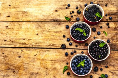 Böğürtlen, yabanmersini, yabanmersini, frenk üzümü ve böğürtlen. Eski ahşap masa arkaplanı, üst manzara