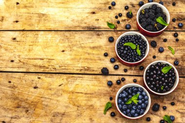 Böğürtlen, yabanmersini, yabanmersini, frenk üzümü ve böğürtlen. Eski ahşap masa arkaplanı, üst manzara