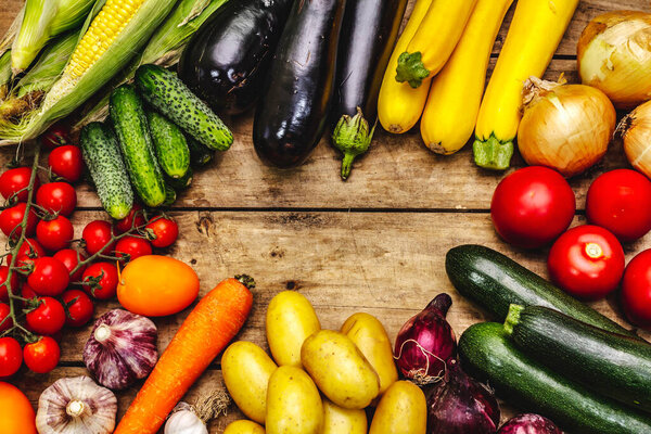 Harvest a variety of ripe vegetables. Fresh cucumbers, tomatoes, eggplants, zucchini, onions, garlic, potatoes, carrots. Old wooden boards background, place for text, top view