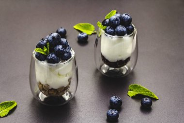 Yabanmersini ve chia tohumlu yoğurt. Sağlıklı ve yararlı kahvaltı konsepti. Olgun böğürtlen, nane yaprağı, siyah taş beton arka plan, kapat