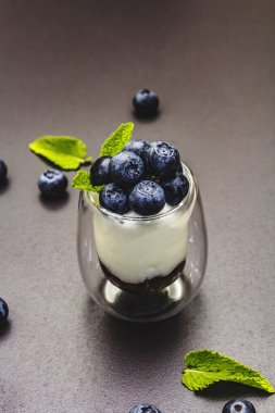 Yabanmersini ve chia tohumlu yoğurt. Sağlıklı ve yararlı kahvaltı konsepti. Olgun böğürtlen, nane yaprağı, siyah taş beton arka plan, kapat
