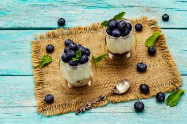 Yabanmersini ve chia tohumlu yoğurt. Sağlıklı ve yararlı kahvaltı konsepti. Olgun böğürtlen, nane yaprağı, trend turkuaz ahşap tahta arka planda gümüş kaşık, kopyalama alanı