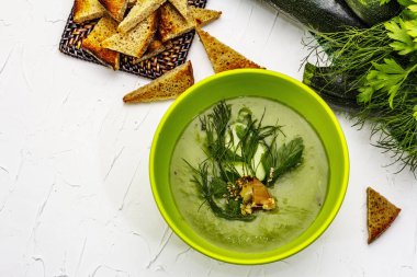 Yeşil kabak kremalı çorba. Sağlıklı vejetaryen yemeği, çıtır tost, susam tohumu, olgun meyveler, taze sebzeler. Beyaz macun arkaplan, üst görünüm
