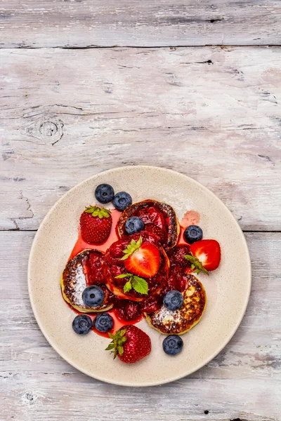 Taze böğürtlen ve çilek soslu süzme peynirli krep. Sağlıklı kahvaltı konsepti. Olgun yaban mersini, mis kokulu nane yaprakları. Tahta kaplama arka plan, üst görünüm