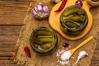 Baharat ve bitkilerle marine edilmiş salatalık turşusu. Cam kavanozlarda geleneksel ev yapımı fermente aperatif. Eski tahta kaplama arka plan, üst görünüm