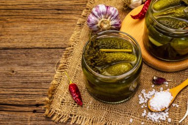 Baharat ve bitkilerle marine edilmiş salatalık turşusu. Cam kavanozlarda geleneksel ev yapımı fermente aperatif. Antika tahta tahta arka plan, kopyalama alanı