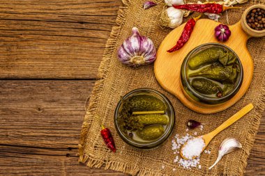 Baharat ve bitkilerle marine edilmiş salatalık turşusu. Cam kavanozlarda geleneksel ev yapımı fermente aperatif. Eski tahta kaplama arka plan, üst görünüm