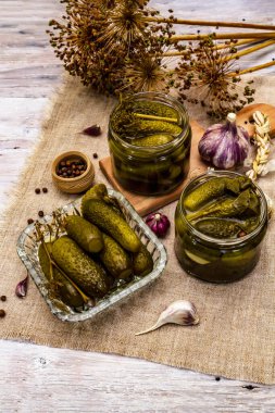 Baharat ve bitkilerle marine edilmiş salatalık turşusu. Geleneksel yeni yıl aperatifleri cam kavanozlar ve kristal tabaklarda. Beyaz tahta arka plan, kapat