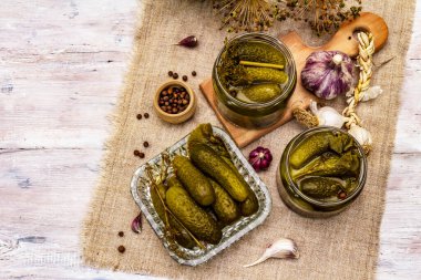 Baharat ve bitkilerle marine edilmiş salatalık turşusu. Geleneksel yeni yıl aperatifleri cam kavanozlar ve kristal tabaklarda. Beyaz tahta tahta arka plan, üst görünüm