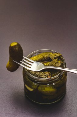 Baharat ve bitkilerle marine edilmiş salatalık turşusu. Geleneksel yeni yıl aperatifi cam kavanozda. Moda siyah taş beton arka plan, kapat