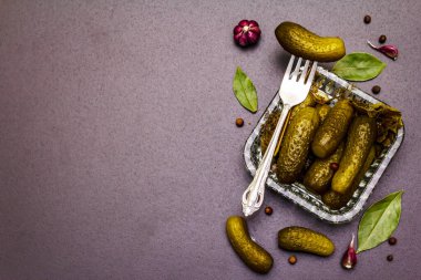 Baharat ve bitkilerle marine edilmiş salatalık turşusu. Geleneksel yeni yıl aperatifleri kristal tabakta. Moda siyah taş arka plan, üst görünüm