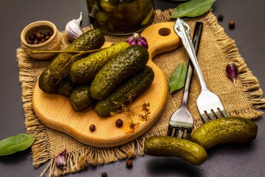 Baharat ve bitkilerle marine edilmiş salatalık turşusu. Geleneksel Doğu Avrupa aperatifleri cam kavanozlarda ve tahta kesme tahtalarında. Moda siyah taş beton arka plan, kapat