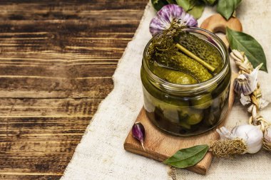 Baharat ve bitkilerle marine edilmiş salatalık turşusu. Geleneksel fermente aperatifler cam kavanozda. Tahta kaplama arka plan, kopyalama alanı