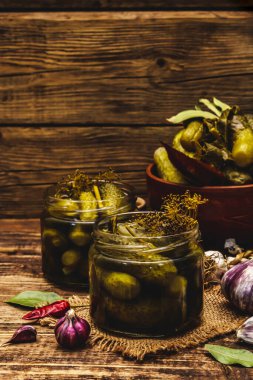 Baharat ve bitkilerle marine edilmiş salatalık turşusu. Geleneksel fermente aperatifler cam kavanozlar ve kil kaselerde. Tahta kaplama arka plan, kopyalama alanı