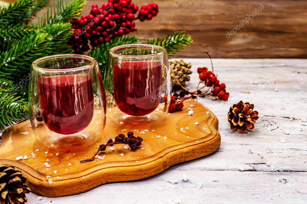 Festive berries liqueur or tincture in double-walled glasses. Ingredient for preparation alcohol cocktail. New Year or Christmas design, white wooden boards background, copy space