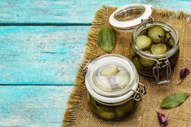 Baharat ve bitkilerle marine edilmiş salatalık turşusu. Geleneksel fermente aperatif cam kavanoz ve seramik kasede. Turkuaz tahta tahtalar arka plan, kopyalama alanı